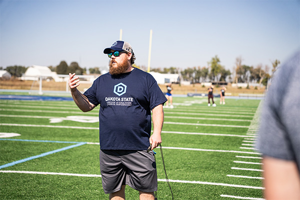 Dr. Luke Chowning teaching students for one of his exercise science classes on the practice football field. 